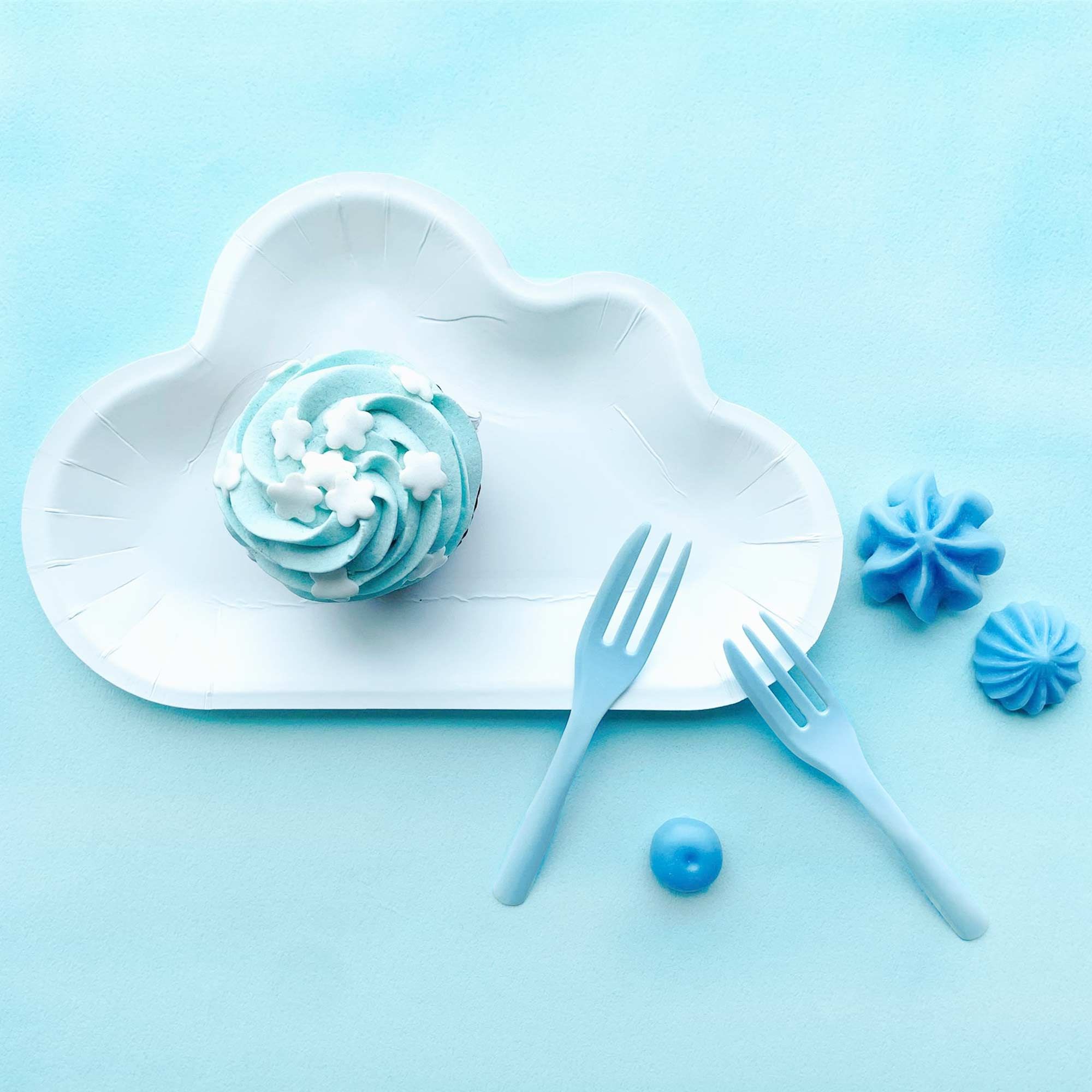 L'assiette en forme de nuage blanc associée à des fourchettes à gâteau bleues crée une atmosphère évoquant un ciel bleu avec des nuages moelleux.